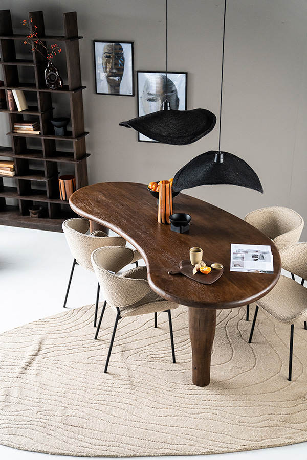 Donkerbruin houten eettafel met tafelblad in organische vorm met daaraan 4 beige eetkamerstoelen in bouclé in de woonstijl Slow Living.