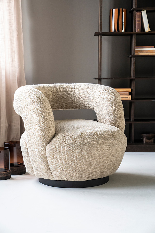 Ronde draaifauteuil met open rugleuning in beige bouclé in kamer met grijze vloer.